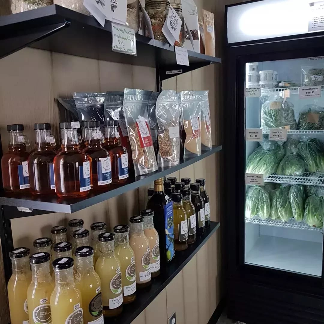 Shelves of local products including sauces, juices, and fresh greens
